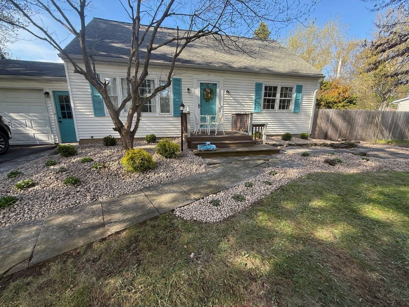 Landscaped front yard with river-rock mulch beds, paver walkway, and deck